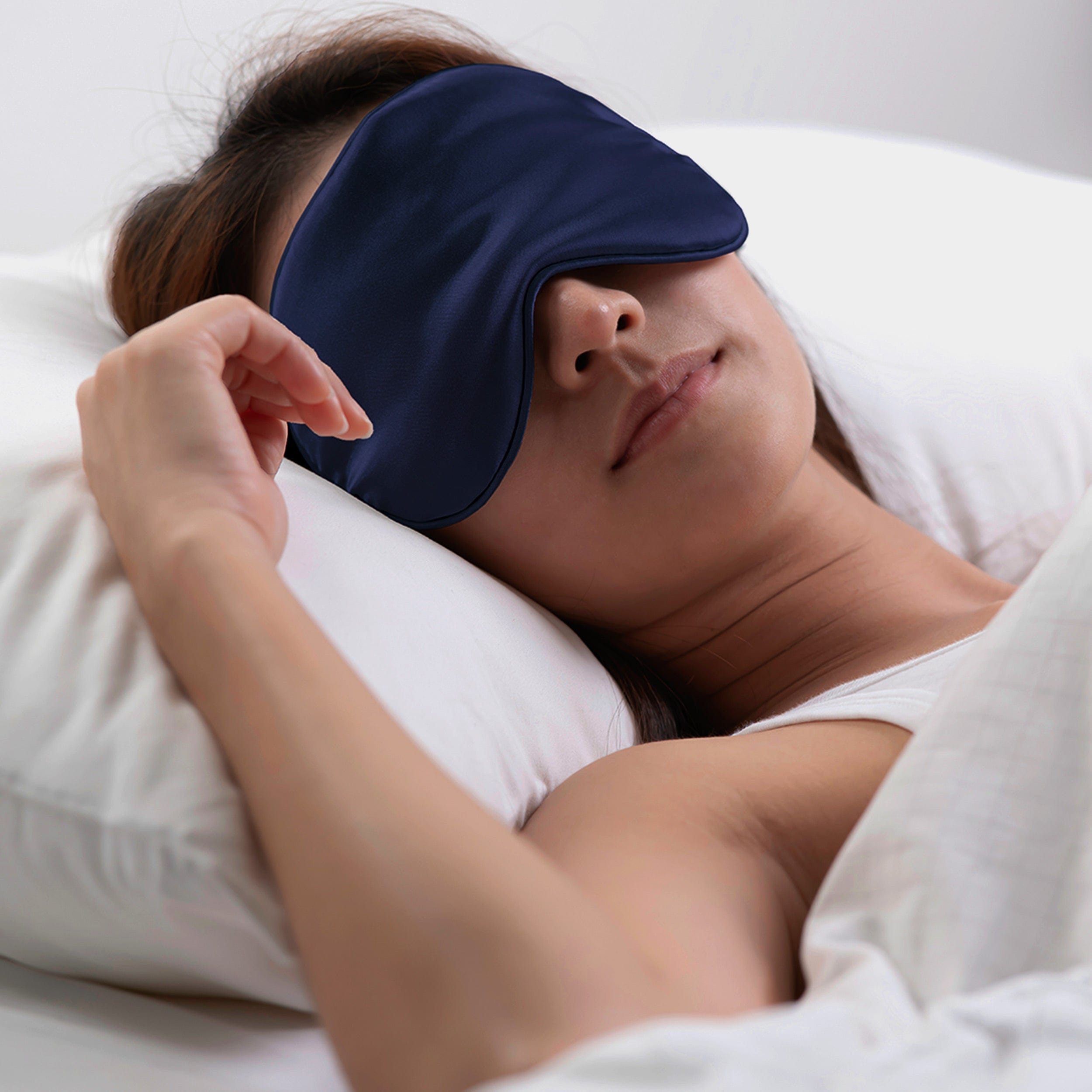 Woman model wearing the 100% silk eye mask, pictured in bed getting a restful sleep.